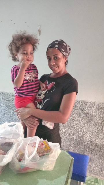 Mother holding her daughter beside a delivery from Cuba Compassion Project